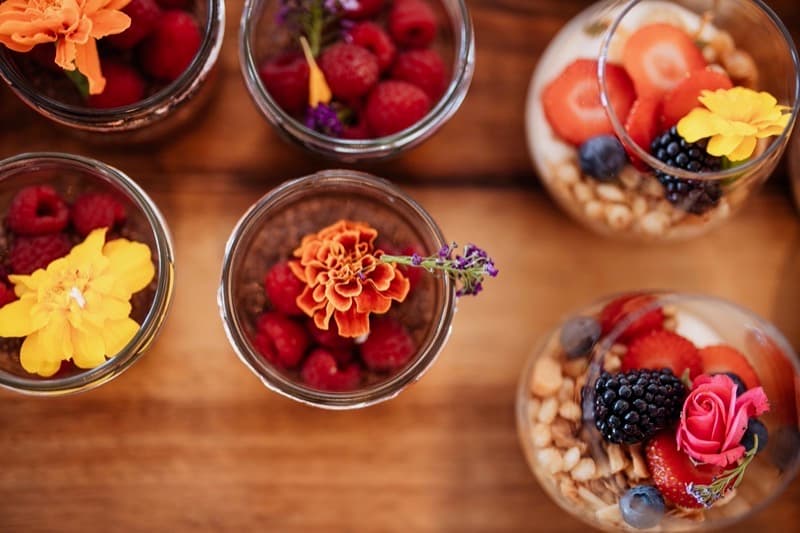 Overhead parfait cups with raspberries and edible marigolds for a baby shower brunch