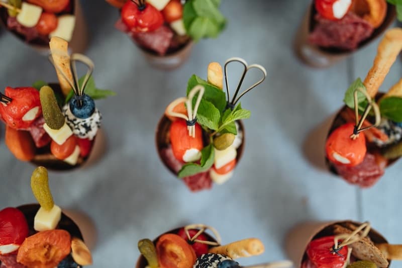 Overhead view of individual antipasto cups with peppadew peppers, cheese, and fresh herbs for an Adelaide cocktail party