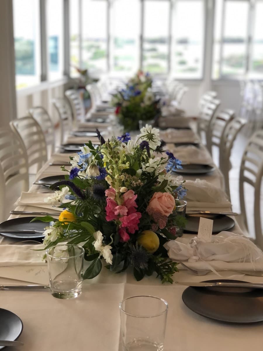 Colourful wildflower table centrepiece on a set reception table with dark plates and name cards