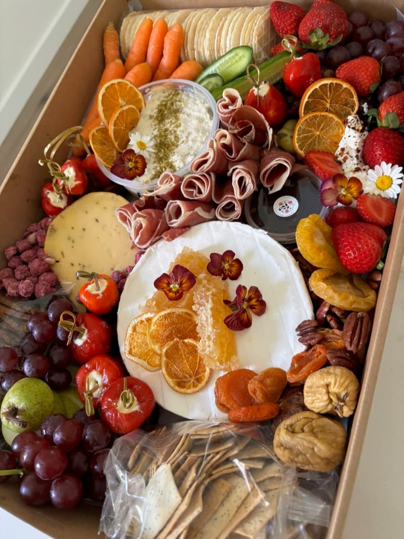 Adelaide grazing box with brie, prosciutto, dried oranges, and edible flowers by Event Gourmet
